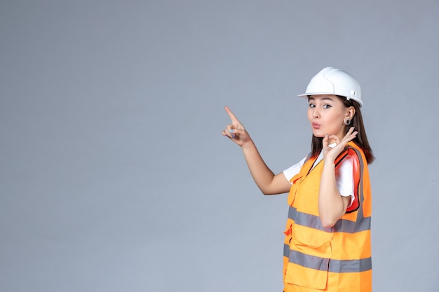 Vista frontal del constructor femenino en uniforme en la pared blanca