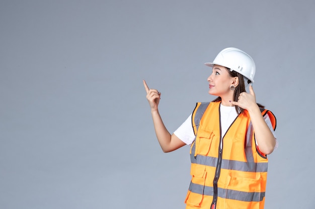 Vista frontal del constructor femenino en uniforme en la pared blanca