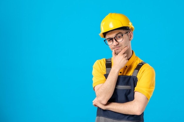 Vista frontal del constructor masculino de pensamiento en uniforme en azul