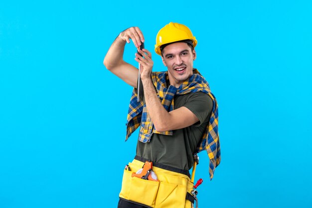 vista frontal, construtor masculino, capacete, segurando, chave de fenda, fundo azul, arquitetura plana, casa, trabalho, edifícios, trabalhador, construtor