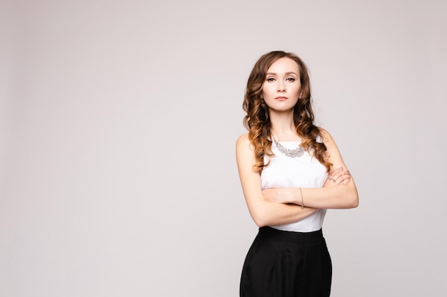 Vista frontal da elegante mulher bem sucedida vestindo roupa inteligente e óculos e posando em fundo isolado Mulher inteligente com braços cruzados, olhando para a câmera no estúdio Conceito de trabalho e negócios