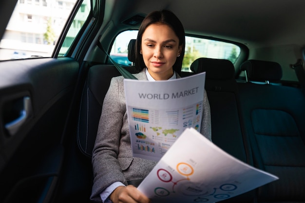 Foto vista frontal da empresária no carro revisando documentos