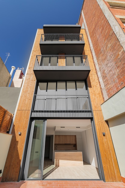 Foto vista frontal da fachada de um edifício contemporâneo de madeira e metal com listras verticais de madeira para fora ...