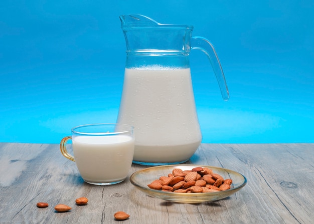 Foto vista frontal da jarra de leite com copo e amêndoas