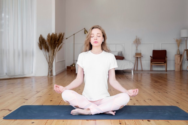 Vista frontal da mulher fazendo yoga em casa