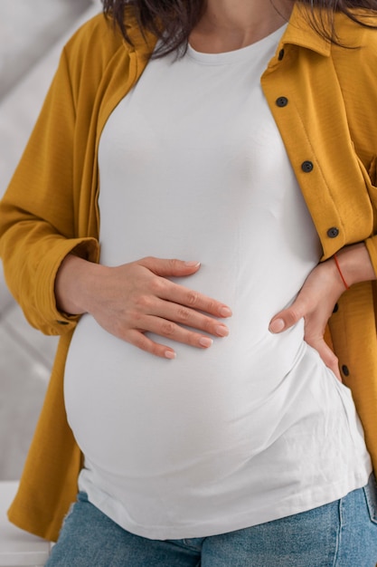 Vista frontal da mulher grávida segurando a barriga