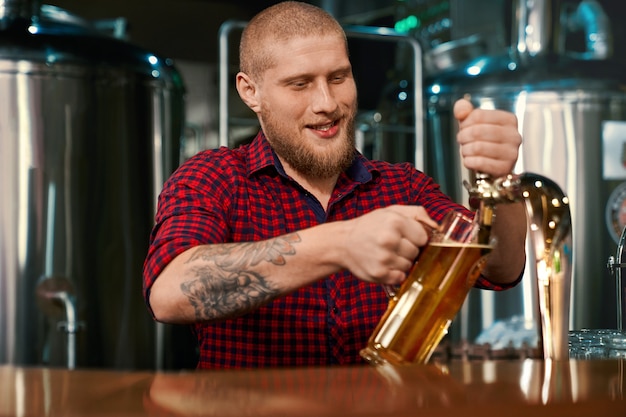 Foto vista frontal de barmen trabalhando em um bar e servindo cerveja em um copo