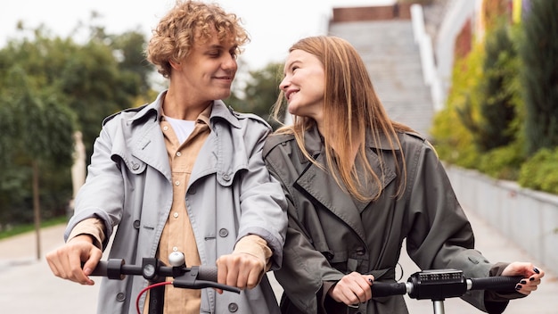 Foto vista frontal de casal usando scooter elétrico ao ar livre