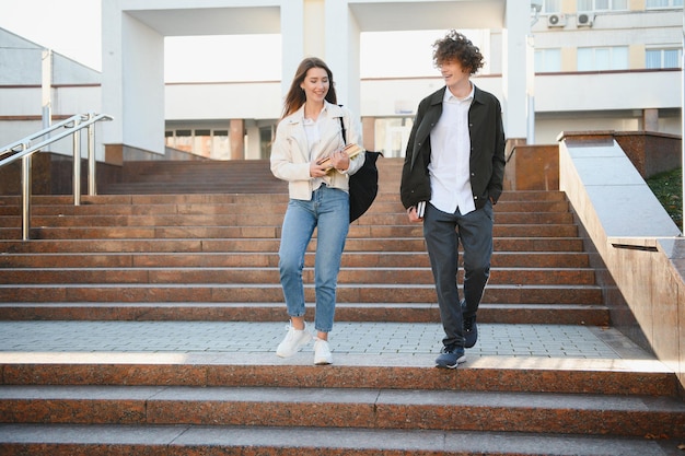 Vista frontal de dois estudantes andando e conversando em um campus universitário