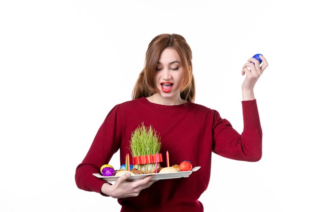 Vista frontal de jovem segurando honca com semeni e novruz doces com ovo azul no fundo branco conceito de primavera etnia cores étnicas feriado