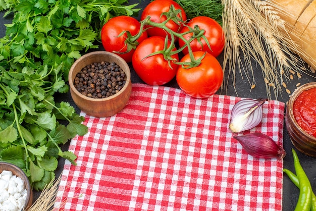 Vista frontal de legumes frescos com pão verde e temperos no escuro