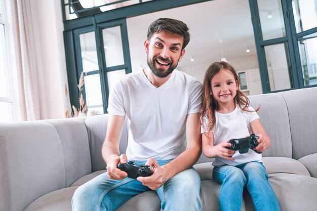 Vista frontal de pai e filha jogando jogo de computador em casa