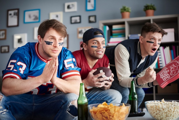 Vista frontal de três homens assistindo futebol americano