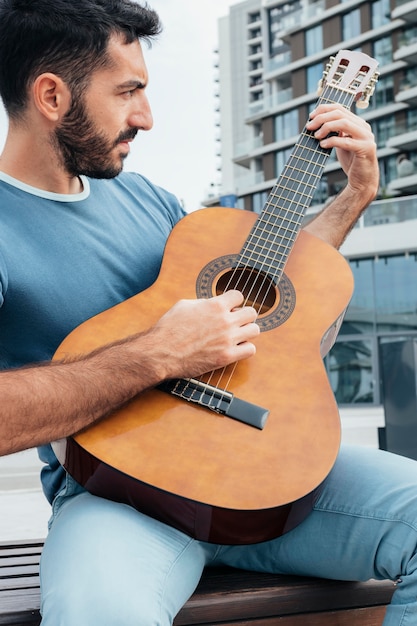 Foto vista frontal de um homem tocando violão