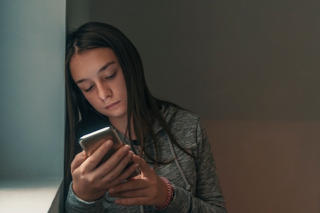 Vista frontal de um telefone de verificação adolescente triste