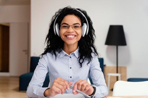 Foto vista frontal de uma adolescente sorridente em casa durante a escola online com fones de ouvido