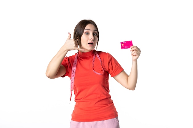 Vista frontal de uma jovem curiosa em redorange blusa mostrando cartão do banco fazendo gesto de me ligar em fundo branco