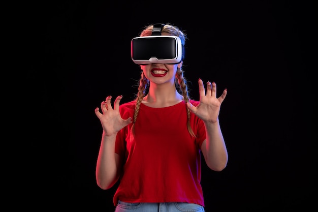 Vista frontal de uma jovem mulher jogando realidade virtual na parede escura
