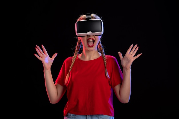 Vista frontal de uma jovem mulher jogando vr na parede escura