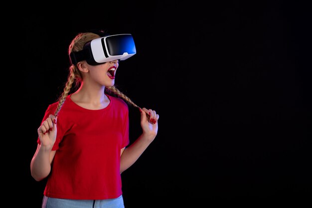 Vista frontal de uma jovem mulher jogando vr na parede escura