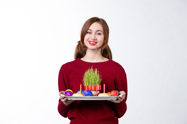 vista frontal de uma jovem mulher segurando honca com doces semeni e novruz no fundo branco cores performer conceito etnia feriado étnico de primavera