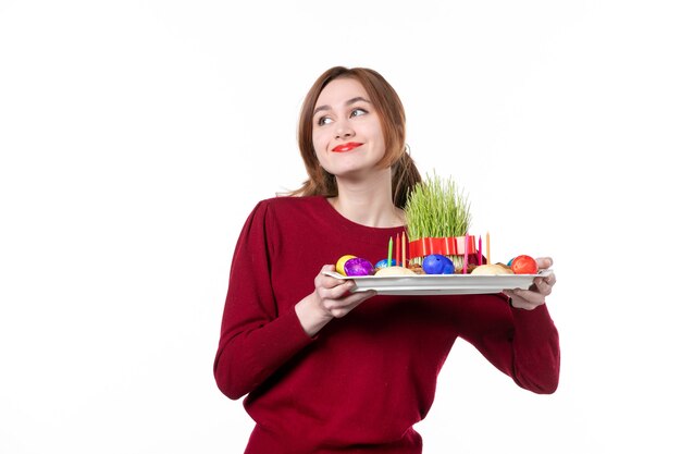 Vista frontal de uma jovem segurando honca com doces semeni e novruz no fundo branco.