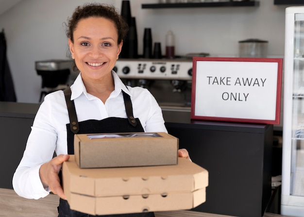 Foto vista frontal de uma mulher de avental segurando comida embalada para viagem