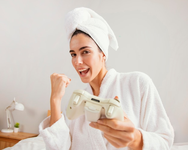 Foto vista frontal de uma mulher jogando videogame em casa após o banho