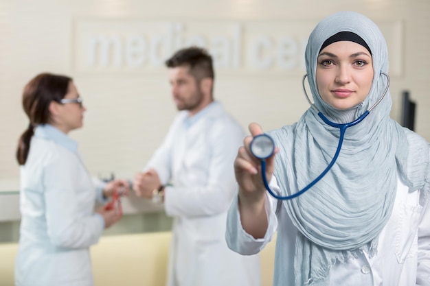 Vista frontal de uma mulher médica árabe mostrando estetoscópio