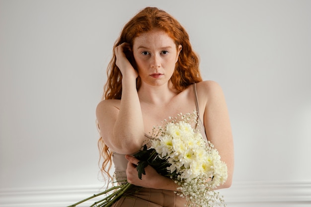 Foto vista frontal de uma mulher sentada e posando com flores da primavera