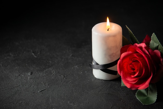 Vista frontal de velas brancas com flor vermelha na parede escura