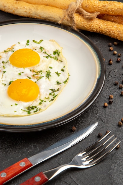 Vista frontal deliciosa tortilla con tenedor y cuchillo sobre fondo oscuro pan almuerzo huevo hervir comida desayuno comida