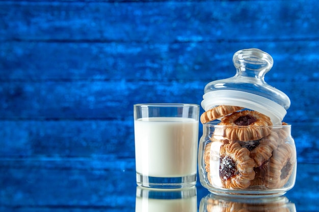 Vista frontal deliciosas galletas dulces dentro de lata con un vaso de leche sobre fondo azul color galleta azúcar comida desayuno pastel comida de la mañana