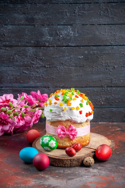 vista frontal delicioso bolo de creme com frutas secas para a páscoa junto com ovos coloridos em fundo escuro cor étnica páscoa colorido ornamentado feriado