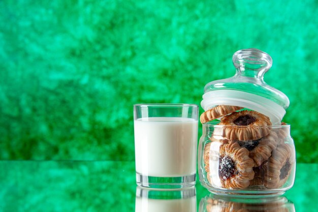 Vista frontal deliciosos biscoitos doces dentro da lata com copo de leite no fundo verde cor açúcar café da manhã bolo de manhã sobremesa refeição biscoito