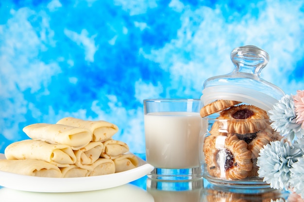 Vista frontal deliciosos panqueques con galletas y leche sobre un fondo azul claro azúcar postre comida galleta dulce desayuno pastel color de la mañana