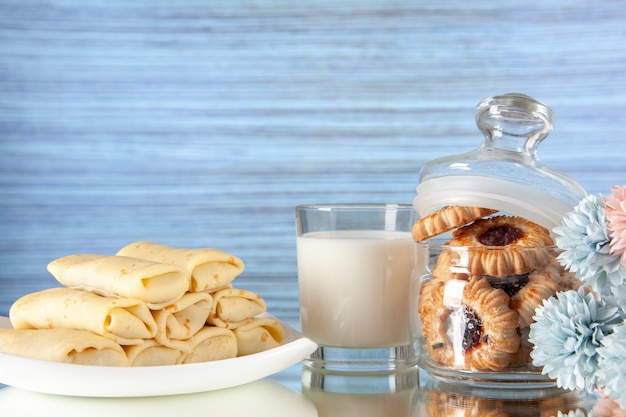 Vista frontal deliciosos panqueques con galletas y leche sobre un fondo claro pastel azúcar postre comida galleta desayuno mañana color dulce