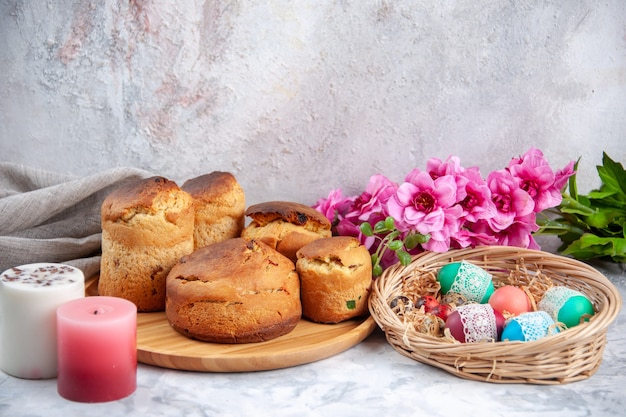 Vista frontal deliciosos pasteles de pascua con flores sobre la superficie blanca pastel de pascua ornamentado colorido concepto de primavera color de postre