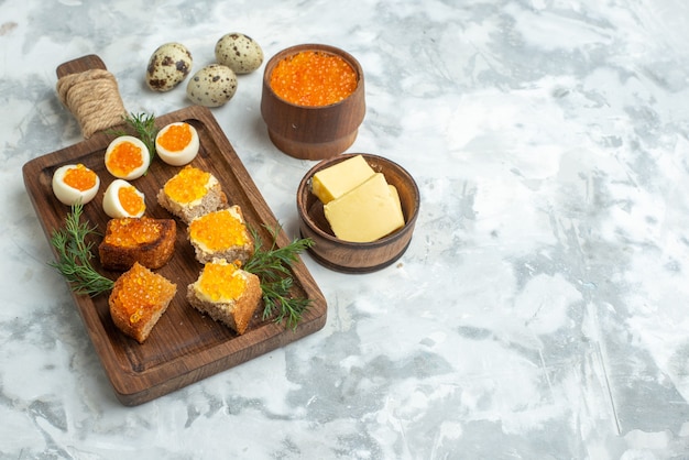 vista frontal deliciosos sanduíches com caviar e ovos cozidos em uma tábua refeição de superfície branca peixes frutos do mar café da manhã almoço comida