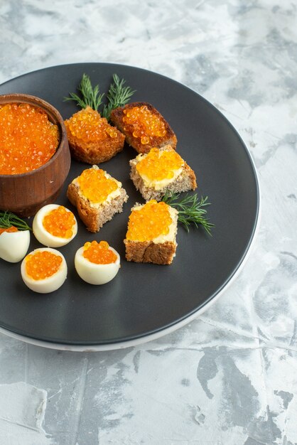 Vista frontal deliciosos sándwiches de caviar con huevos cocidos dentro de la placa fondo blanco desayuno comida mariscos pescado almuerzo tostadas pan