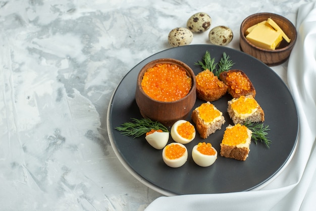 Vista frontal deliciosos sándwiches de caviar con huevos cocidos dentro de un plato fondo blanco mariscos desayuno comida almuerzo tostadas pan pescado comida