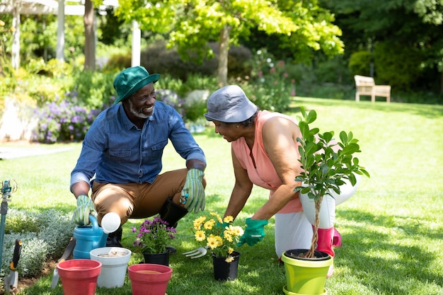 Vista frontal do casal afro-americano sênior no jardim, jardinagem e conversando. Família aproveitando o tempo em casa, conceito de estilo de vida