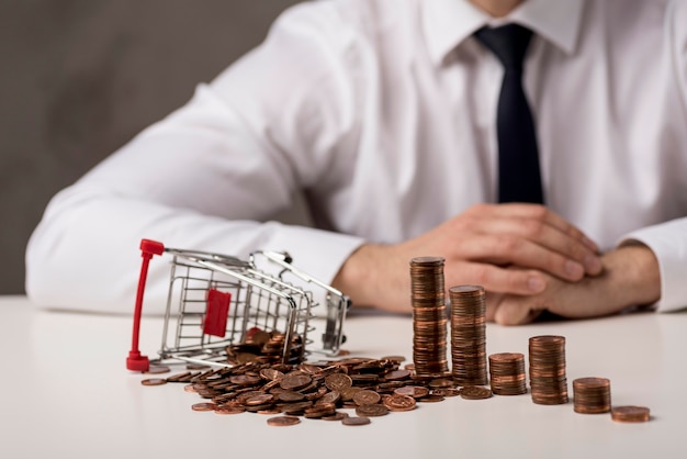 Vista frontal do empresário com moedas e carrinho de compras