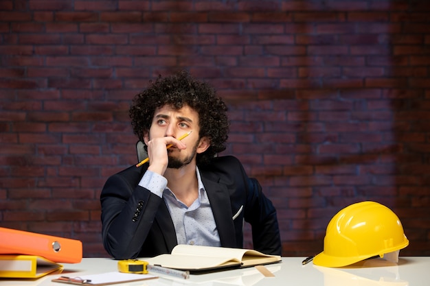 vista frontal do engenheiro estressado sentado atrás do local de trabalho no plano de terno construtor de negócios trabalho ocupação empreiteiro projeto trabalho corporativo