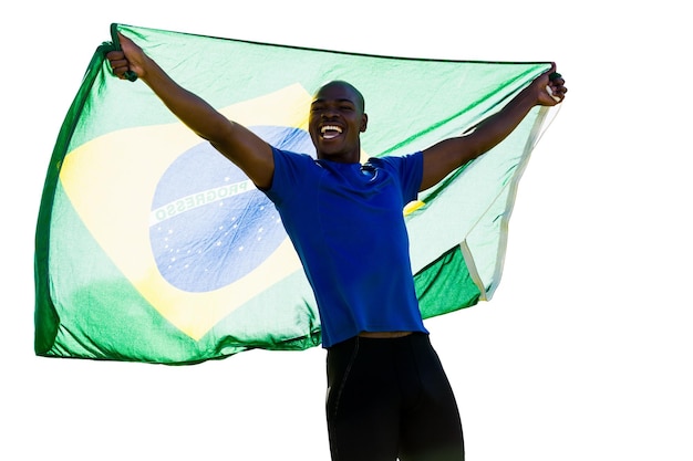 Vista frontal do esportista brasileiro está sorrindo e levantando uma bandeira