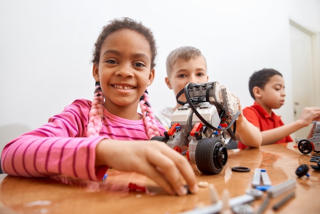 Vista frontal do kit de construção para grupo de três crianças multirraciais criando brinquedos