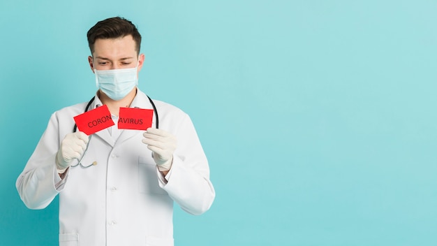 Vista frontal do médico segurando papel rasgado com coronavírus e cópia espaço