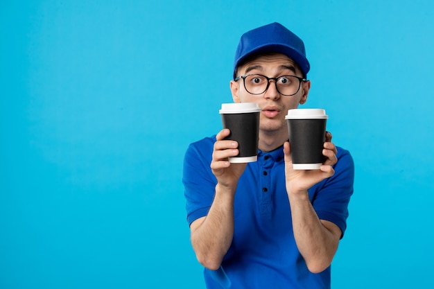 Vista frontal do mensageiro masculino de uniforme azul com café no azul