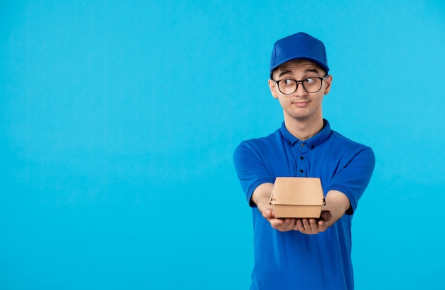 Vista frontal do mensageiro masculino de uniforme azul com um pequeno pacote de comida na cor azul
