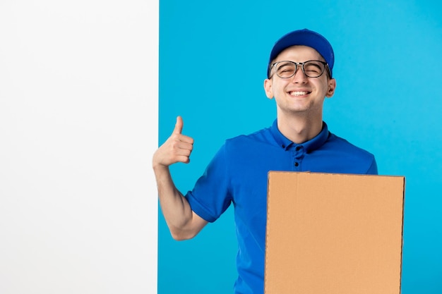 Vista frontal do mensageiro masculino sorridente com uniforme azul e pizza no azul